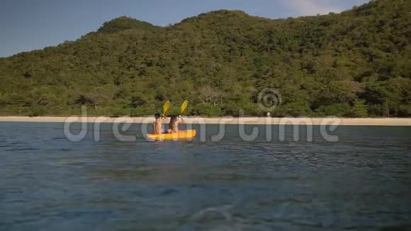年轻人在黄色的独木舟上划着沙滩上的热带海滩享受美好的假期视频的预览图