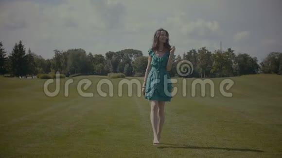 光着脚在绿草地上散步的快乐女子视频的预览图
