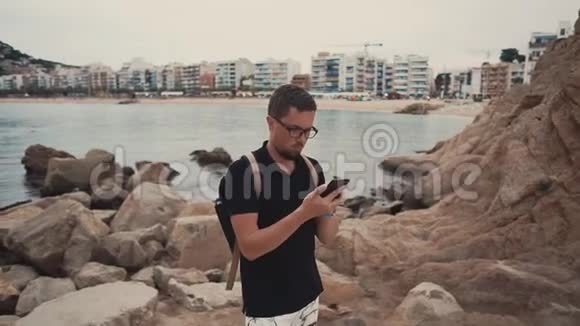 男人在看照片在电话里看信息站在海湾和城市的对立面视频的预览图