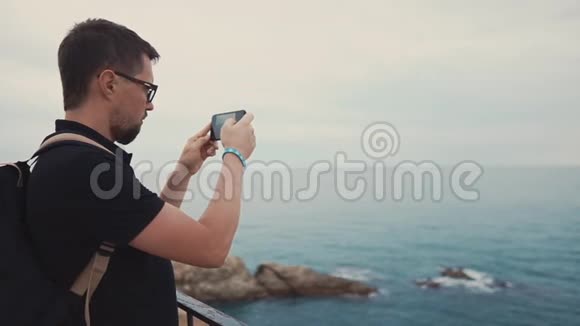 男性游客正在黄昏时拍摄海景使用智能手机摄像头视频的预览图