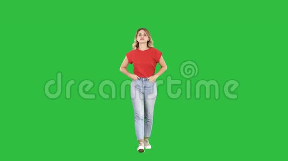 金发女人走着双手插在口袋里和镜头在绿色屏幕上交谈Chroma键视频的预览图