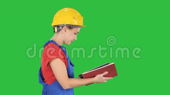女建筑工人戴着安全帽和工作服在绿色屏幕上检查清单Chroma键视频的预览图