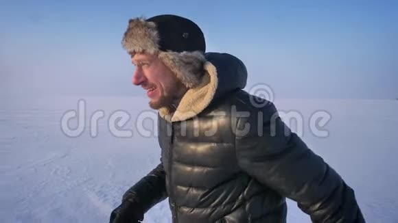 雪场上穿着毛皮帽子和保暖外套的跑步者的肖像视频的预览图
