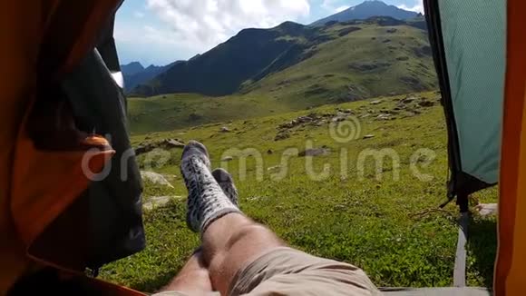 穿袜子的男腿在绿色山谷的帐篷里欢快地移动视频的预览图