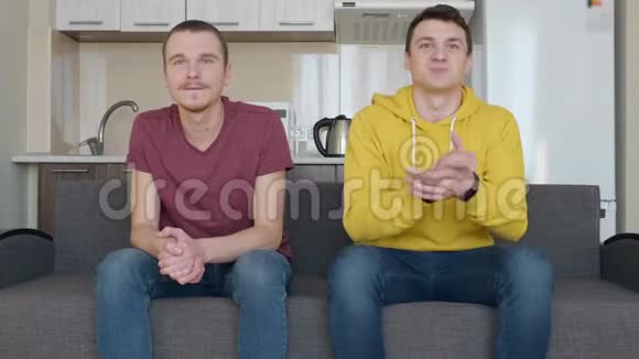 两个人坐在沙发上看着足球比赛的决定性时刻视频的预览图