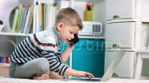 一个学龄前的男孩正在用手提电脑用手机说话视频的预览图