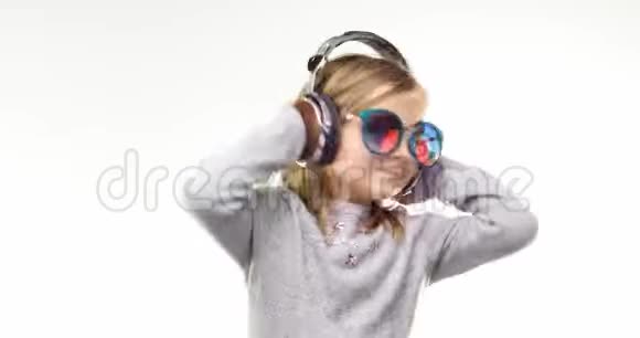 美丽快乐有趣的年轻孩子金发女孩带着太阳镜听音乐使用耳机和跳舞个人行动视频的预览图