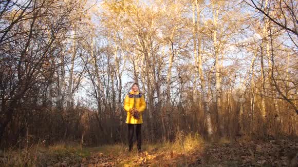 快乐的少女在秋天的公园里把黄叶扔到顶上慢动作视频的预览图