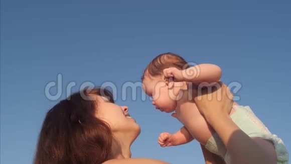 妈妈抱着宝宝玩抱在蓝天背景下慢动作视频的预览图