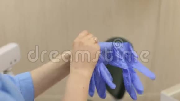 一位女牙医的特写她的手在办公室里戴上蓝色消毒手套视频的预览图