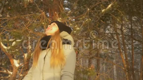 快乐的少年女孩在冬天的松树森林里享受雪阳光明媚的一天戴上头巾视频的预览图