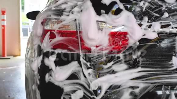 洗车洗车机清洗汽车车上覆盖着白色的冲洗泡沫视频的预览图