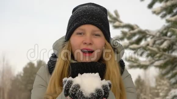 快乐的年轻女孩冬天的衣服吹雪冬天的背景视频的预览图