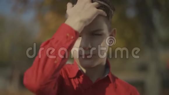 一个小男孩的肖像用手纠正头发可爱的微笑视频的预览图