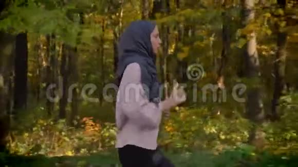 在秋天的森林里戴着头巾的年轻穆斯林女孩在侧面剪下的肖像视频的预览图