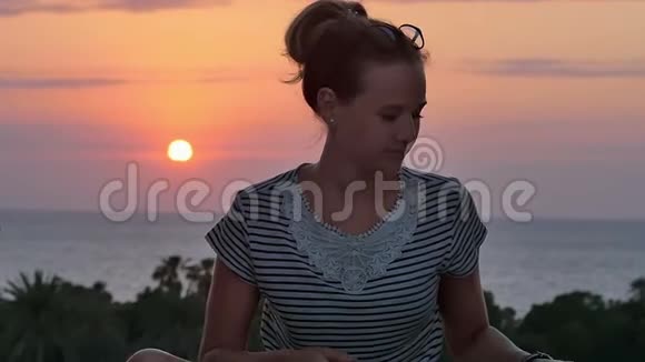 坐在海边欣赏日落的年轻女子视频的预览图