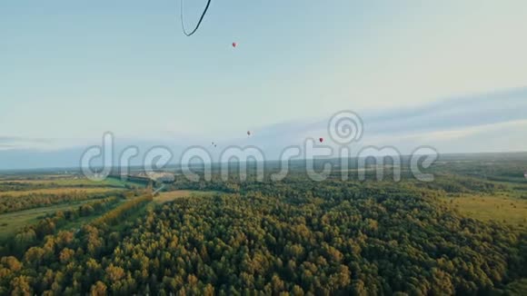 在绿色森林上空飞行的大不同的气球从气球篮中射击视频的预览图