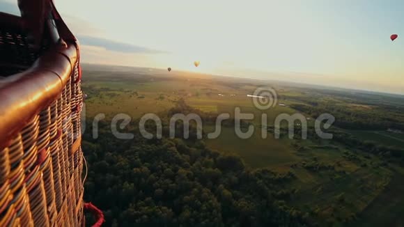在绿色的田野和森林上空飞行的大不同的气球从气球篮中射击视频的预览图