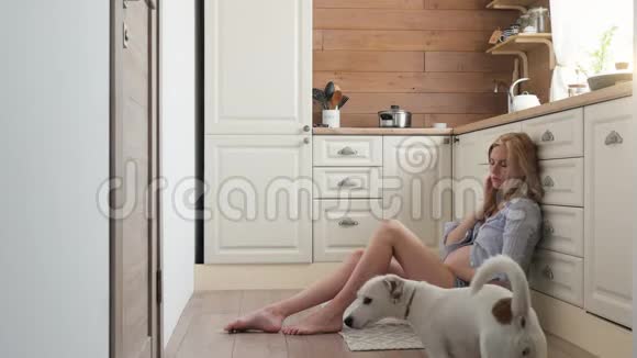 穿睡衣的孕妇坐在厨房的地板上穿短裤和衬衫的女人坐在上面喝茶视频的预览图