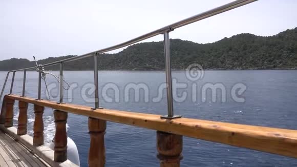 在海上雾蒙蒙但阳光明媚的一天通过游轮栏杆观看Kekova岛附近的土耳其海岸视频的预览图