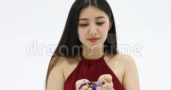亚洲女人吹着五颜六色的闪亮纸屑视频的预览图