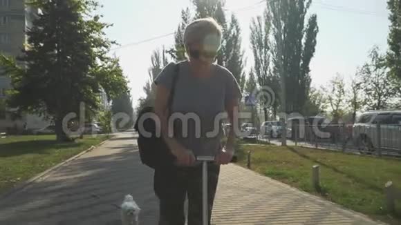 快乐的成年女人在公园里骑滑板车带着狗的男孩靠近母亲视频的预览图