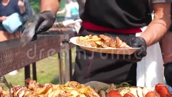 街头美食节一位穿着黑色衣服和手套的厨师把油炸食品铺在盘子上土豆烤香肠肉视频的预览图