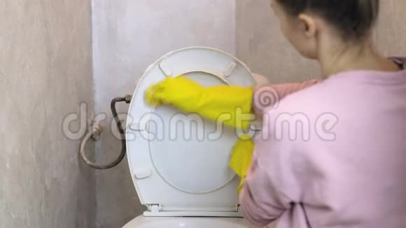 女人用黄色橡胶手套用海绵清洗白色马桶视频的预览图