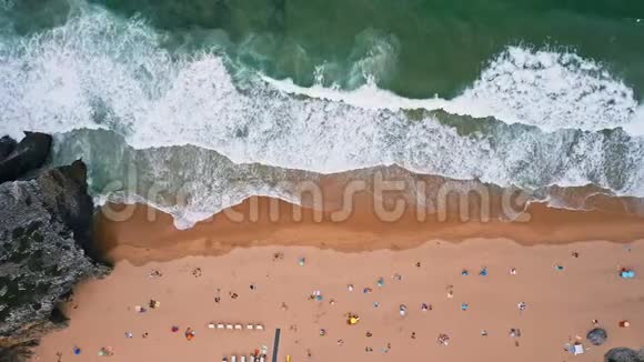 4普拉亚达阿德拉加海滩的空中镜头白色大西洋海浪随着游客向沙滩翻滚辛特拉视频的预览图