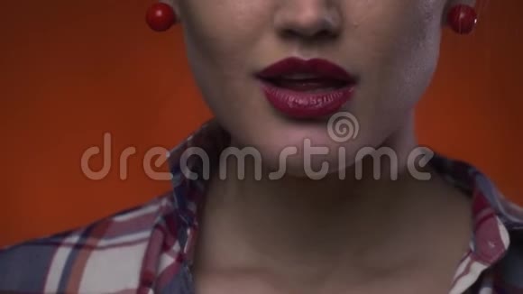 一位可爱的女士用红色口红咬着五颜六色的棒棒糖视频的预览图