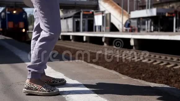 女人腿在铁路站台等火车在后面有一列火车经过视频的预览图