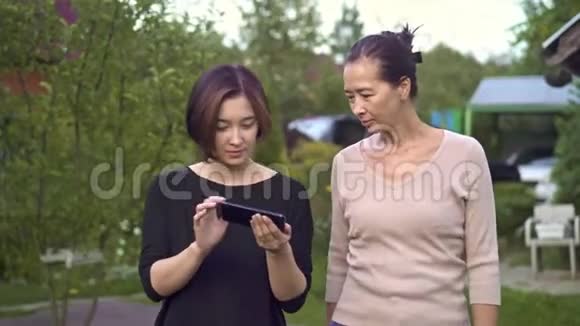 母女俩在智能手机上散步和看照片视频的预览图