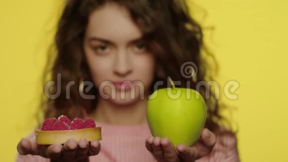 在工作室里年轻女子选择苹果代替蛋糕作为饮食营养视频的预览图