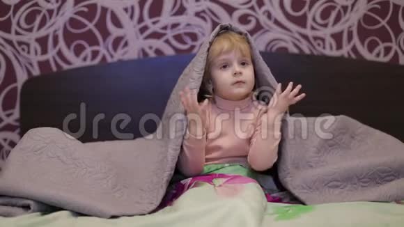 快乐的小女孩躲在毯子下面看电视儿童睡眠概念视频的预览图
