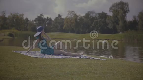 戴着太阳帽的快乐女人在湖边放松视频的预览图