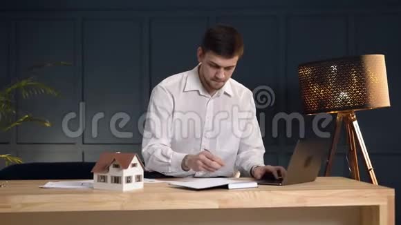 严肃的男性房地产经纪人在笔记本电脑上做一些笔记视频的预览图