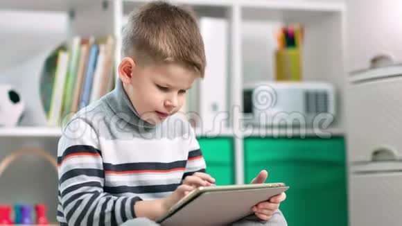 一个小男孩正在用他的平板电脑上网视频的预览图