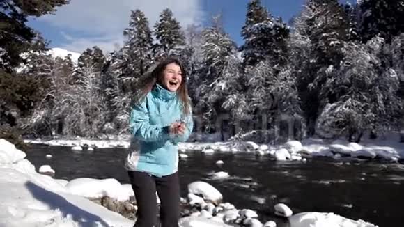 迷人的女孩扔雪球她穿着一件明亮的蓝色羽绒大衣没有头饰因玩耍而兴奋视频的预览图