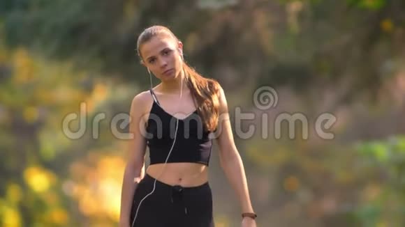 穿着连衣裙的年轻女孩做热身运动并开始在秋季公园跑步的特写照片视频的预览图