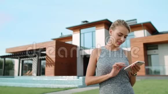 放松的女人在豪宅附近发短信在别墅附近的漂亮女人视频的预览图