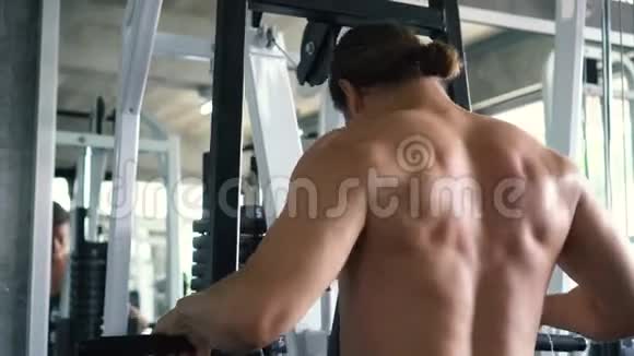 无衫肌肉男在健身房的机器上做坐索排运动视频的预览图