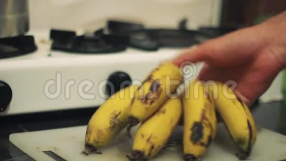 男人把成熟的农场香蕉水果放在家里厨房的桌子上视频的预览图