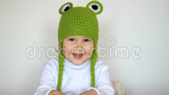 戴着绿帽子的滑稽女孩笑着笑着可爱的快乐宝宝玩和看相机特写肖像视频的预览图