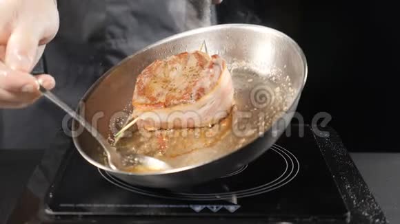 肉牛排是用油煎的油煎的锅上是油厨师用勺子把油倒在牛排上慢动作特写视频的预览图