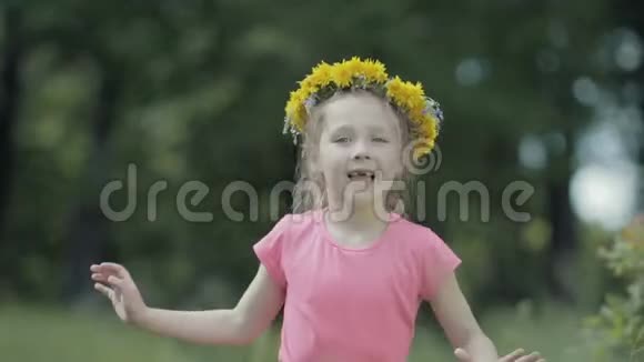 没有门牙的孩子微笑着在蒲公英花圈的头上唱一首歌视频的预览图