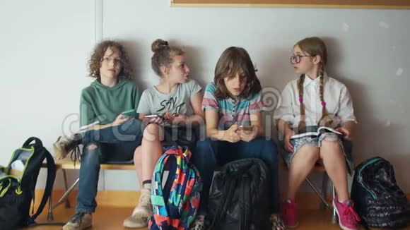 青少年在课间休息时每个人都看他们的智能手机一个女孩在读一本书她很无聊视频的预览图