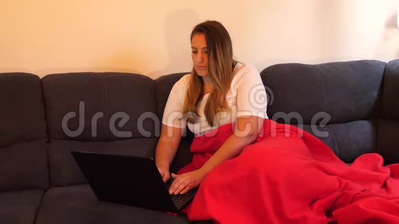女性在家工作在电视前的沙发上工作数字游牧生活方式视频的预览图