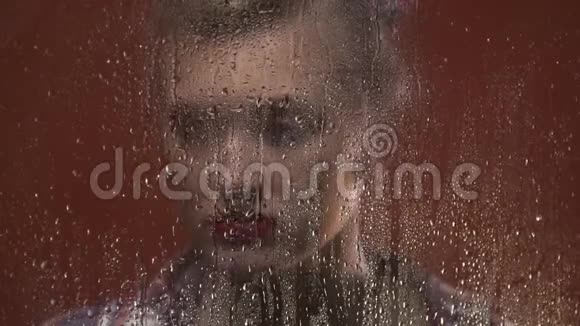 带着红口红的伤心女人透过窗户看着雨打湿了视频的预览图