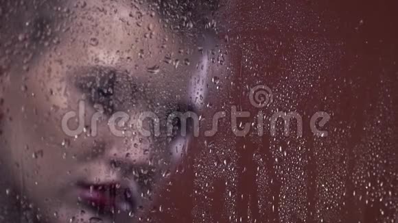 带着红色耳环的复古金发女人很伤心窗户上的雨滴关上视频的预览图