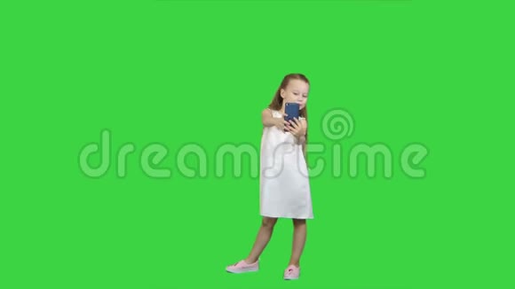 快乐的小女孩用智能手机在绿色屏幕上自拍Chroma键视频的预览图